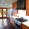 A distressed steel hood with dome head copper rivets helps anchor a pleasant California bungalow kitchen, by Archive Designs.