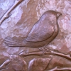 An exquisitely engraved Blackcapped-Chickadee in repoussé occupies a thicket of wild roses on a hammered copper vessel.
